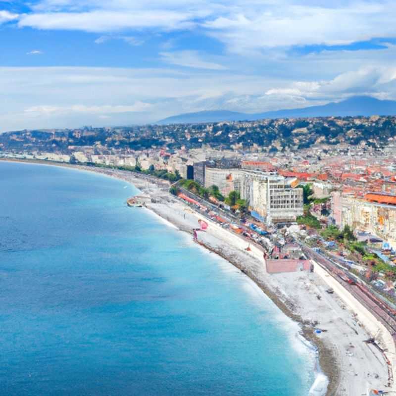 Two couples strolling along the sun-kissed Promenade des Anglais in Nice, France, reveling in the azure waters and vibrant atmosphere that make this coastal gem a winter wonderland during their extended 3&#45;week escape.